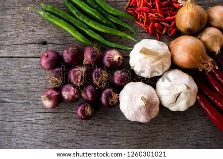 Mixed herbs contain of Chillies, Onions and garlics for cooking on wooden background.
