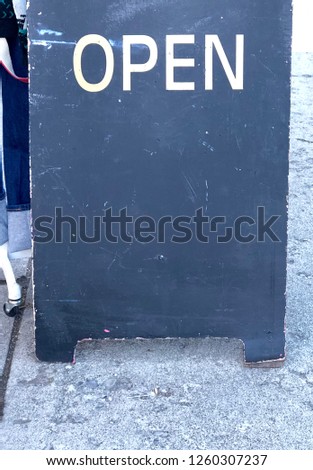 Close up view of chalkboard sidewalk sign with the word open. Area below to add text