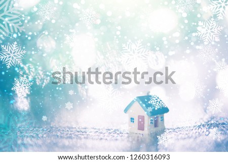 miniature house with blue roof on blurred Christmas decoration background.Little houses on snowy background.