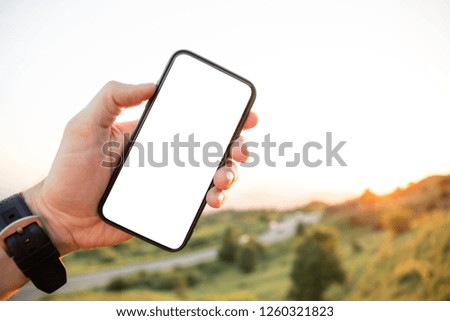 Hand of holding smartphone with white screen on nature background