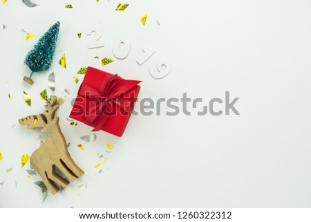Table top view of Merry Christmas decorations & Happy new year 2019 ornaments concept.Flat lay essential difference objects gift box & pine tree with golden confetti on modern white paper background.