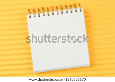 open notebook on corrugated yellow background top view, spiral notepad with blank sheet, flat lay. school concept, desktop of businessman.