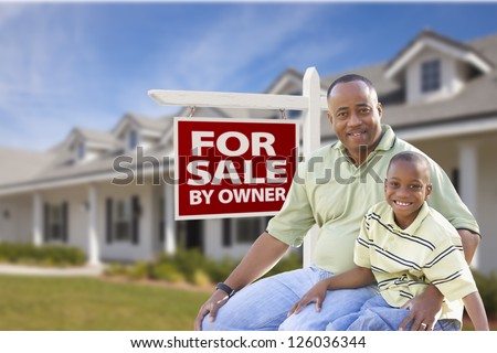 African American Father and Son In Front of For Sale By Owner Real Estate Sign and House.