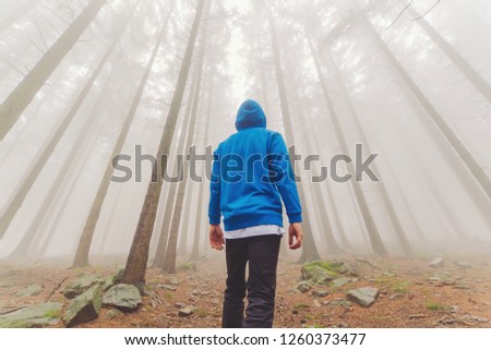 Man in foggy path in autumn fantasy forest.