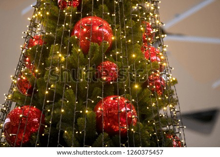 Decorated Christmas tree closeup. Red and golden balls and illuminated garland with flashlights. New Year baubles macro photo with bokeh. Winter holiday light decoration