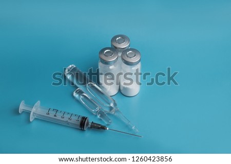 medical ampoules and syringe isolated on blue background 
