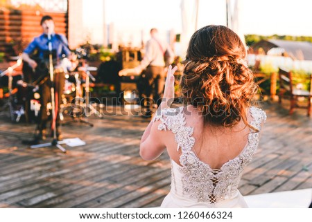 The bride listens to a performance the of favorite band. A wedding with music band. The woman claps and sings along with a song