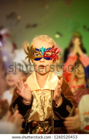 Beautiful happy boy in a carnival costume for The new year holiday, Christmas clapping his hands