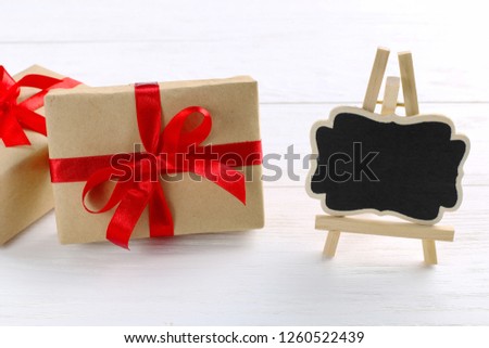 Gift with red ribbon and hearts on white wooden background. Women's Valentine's Day. Place for text, copy space.