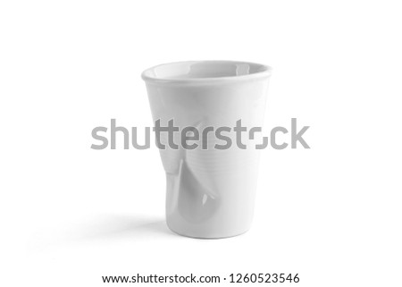 Design crumpled ceramic coffee cup as plastic one time cup isolated on white background. Funny white ceramic empty coffee cup.
