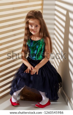 Portrait of a beautiful little girl in the rays of light. The concept of style and fashion.
