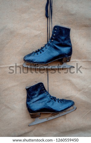 old ice-skates hang on rope on jute background
