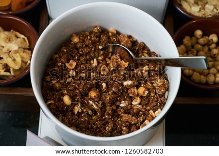 Hotel morning breakfast buffet food set with corn flakes, chocolate and cocoa cereals, and milk in the glass container with white bowls. Buffet catering service and healthy vegetarian food concept. 