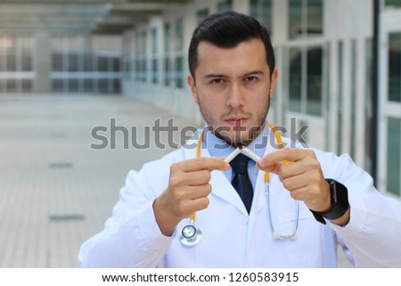 Serious doctor breaking a cigarette 