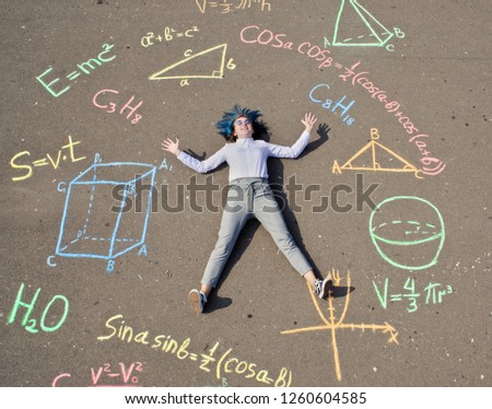 schoolgirl laying on a asphalt with chalk drawn mathenatics formulas and geometric figures