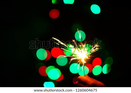 christmas sparklers over dark background with green, red, blue lights