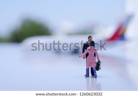 Travel concept.Traveler miniature peoples figure with bag walking on airport with airplane model.