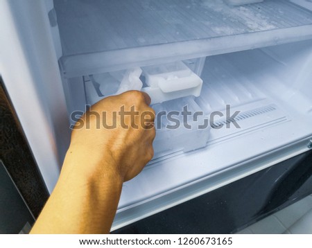 Man hand twistding for ice from theice maker in new refrigerator.Closed up.