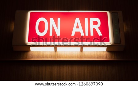 On Air sign icon glowing on the wooden wall of sound recording studios, live broadcast radio production room Royalty-Free Stock Photo #1260697090