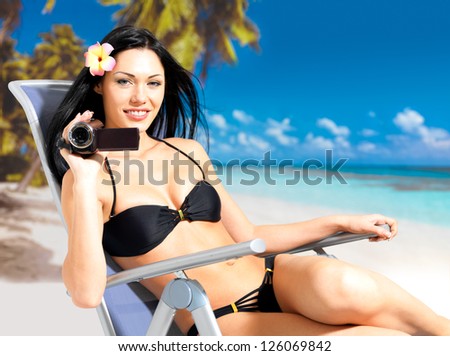 Happy woman with a video camera  on the beach