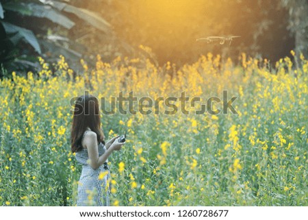 Woman with remote control and flying surveillance drone flower background