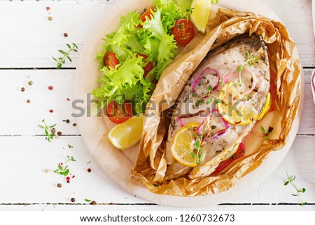 White fish steak (carp) baked in parchment paper with vegetables. Fish dish. Top view