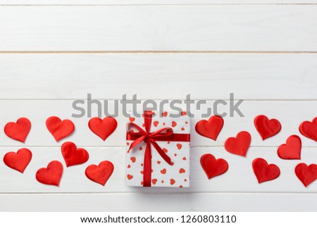 Valentine or other holiday handmade present in paper with red hearts and gifts box in holiday wrapper. Present box gift on white wooden table top view with copy space, empty space for design.