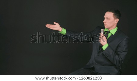 The leading show or businessman with microphone in the hands is showing on a copy space isolated on black background.
