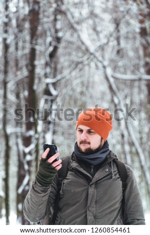 a man uses a mobile phone in a snowy forest. Mobile networks. Addiction. Call for help. Call rescue. vertical photo. battery discharge and signal loss, smartphone for tourism and trips