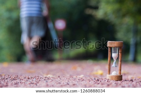 
Sand clock on the background of the outgoing person. Abstraction of the passing time