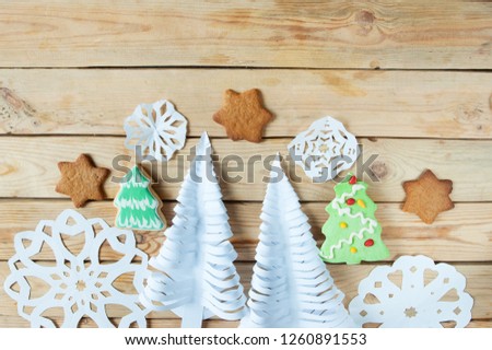 Christmas trees and snowflakes cutting out of paper lie on a wooden background, merry Christmas and happy new year concept