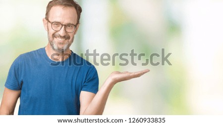 Handsome middle age hoary senior man wearin glasses over isolated background smiling cheerful presenting and pointing with palm of hand looking at the camera.