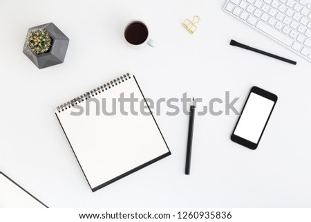 Office desk table with paper notebook, phone and cup of coffee and supplies. View from above