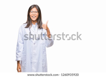 Young asian doctor woman over isolated background doing happy thumbs up gesture with hand. Approving expression looking at the camera with showing success.