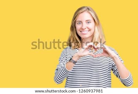 Beautiful young woman wearing stripes sweater over isolated background smiling in love showing heart symbol and shape with hands. Romantic concept.