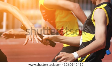 Professional Athlete passing a baton to the partner against race on racetrack.selective focus. Royalty-Free Stock Photo #1260942412