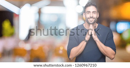 Young handsome man wearing sweater over isolated background praying with hands together asking for forgiveness smiling confident.
