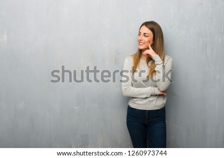 Young woman on textured wall thinking an idea while looking up