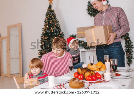 Father gives his family Christmas gifts at the Christmas table