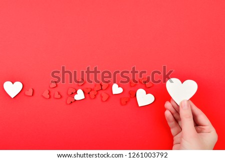 Red and white hearts on a red background. Woman holding white heart. Copy space.