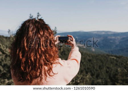 Happy woman on the sunset in nature in autumn taking a picture with mobile phone. fun outdoors