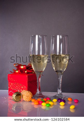 gift in a red box next to lie candy and glasses with wine