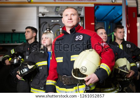 Photo of four fire men and women looking in different directions on background of fire truck