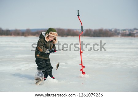 boy fishing on winter. Cute boy catches fish in the winter lake. Winter. Outdoor