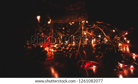 Christmas, New Year. Bank with cones. Dark background. Defocusing. Glowing garland.