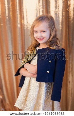 Portrait of a little beautiful girl on a background of golden sequins