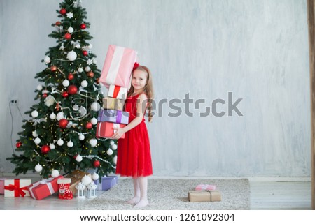 little girl opens Christmas gifts at the Christmas tree new year holiday house