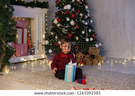 little boy opens gifts at Christmas New Year holiday lights