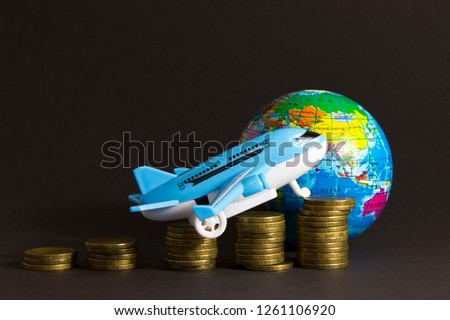 Toy plane on  background of  globe and  coins. Concept of airfare, air travel, air insurance.