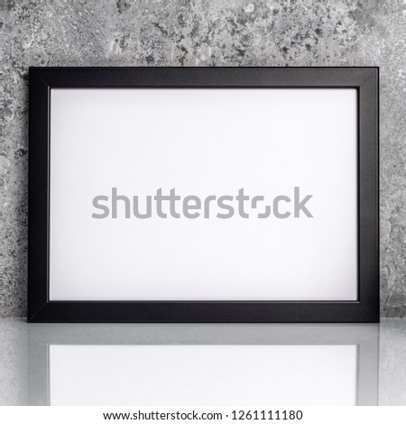 Rectangular black frame poster on white floor and stone wall. Industrial style. Mockup. Front view
